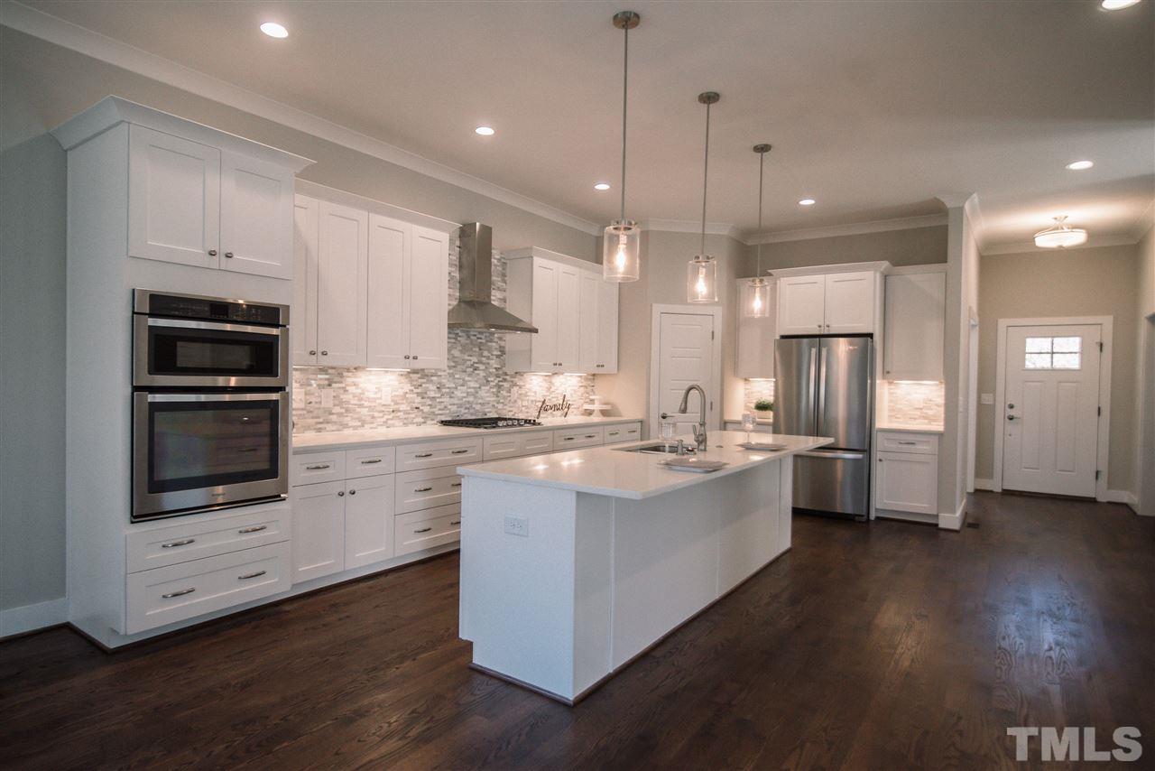 1508 East Lane Street Raleigh, NC 27610 - Photo 11 of 30 a large kitchen with white cabinets and stainless steel appliances