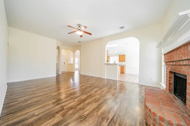 an empty room with wooden floor fireplace and windows