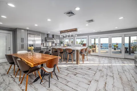 a dining hall with stainless steel appliances granite countertop a living room dining table and chairs with wooden floor