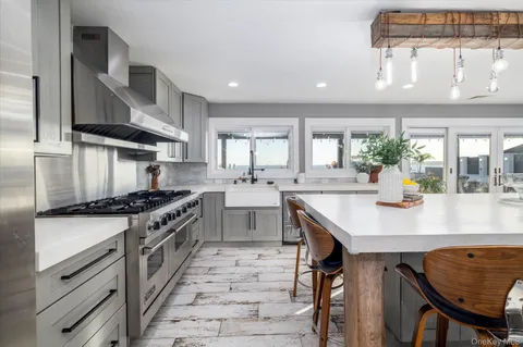 a kitchen with stainless steel appliances granite countertop a refrigerator a sink a dining table and chairs