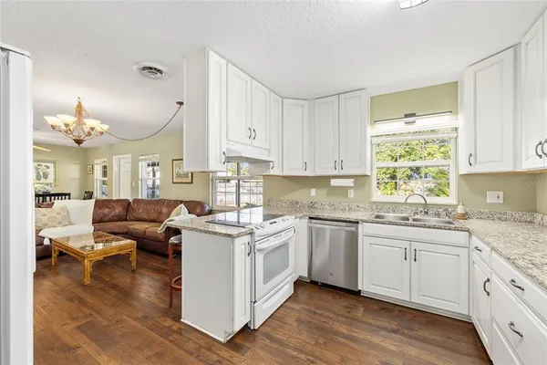 a kitchen with stainless steel appliances granite countertop wooden cabinets a sink dishwasher a stove and a refrigerator