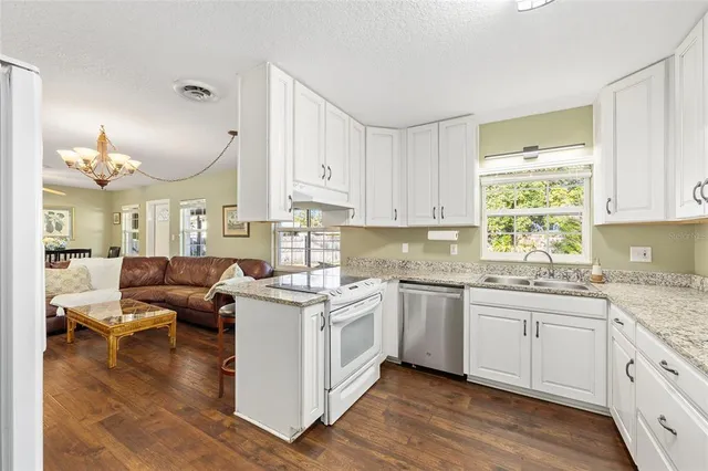 a kitchen with stainless steel appliances granite countertop wooden cabinets a sink dishwasher a stove and a refrigerator