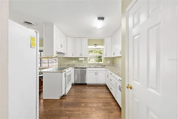 a kitchen with granite countertop white cabinets and white appliances