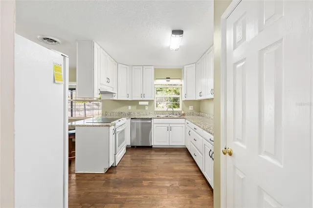 a kitchen with granite countertop white cabinets and white appliances