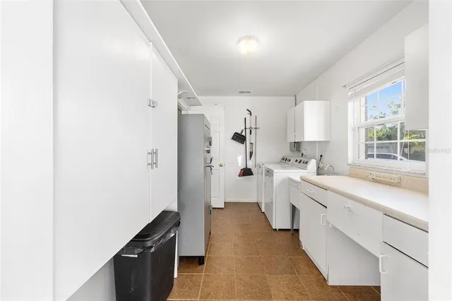 a large white kitchen with a sink and dishwasher a stove top oven with wooden floor