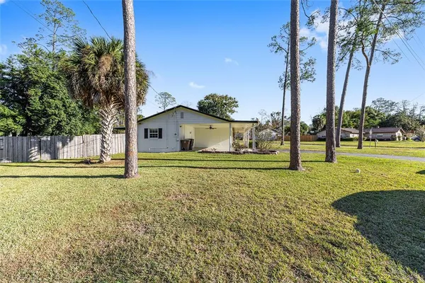 a white house with a big yard and palm trees