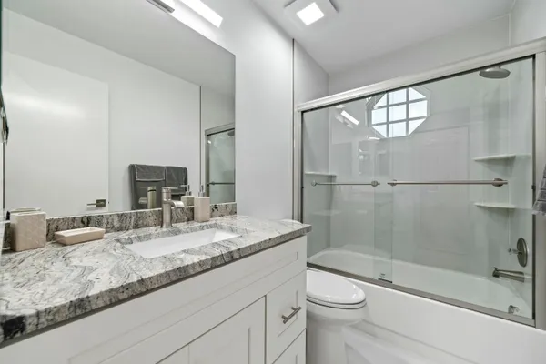 a bathroom with a granite countertop sink toilet and shower