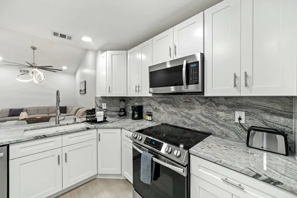 a kitchen with granite countertop white cabinets stainless steel appliances and a sink