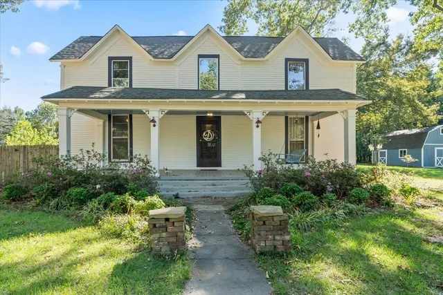 a view of a white house with a clock and a yard