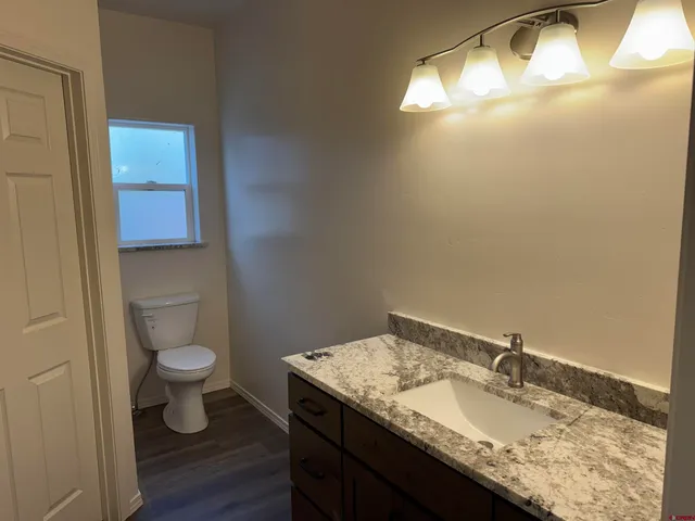 a bathroom with a granite countertop sink a toilet and a mirror