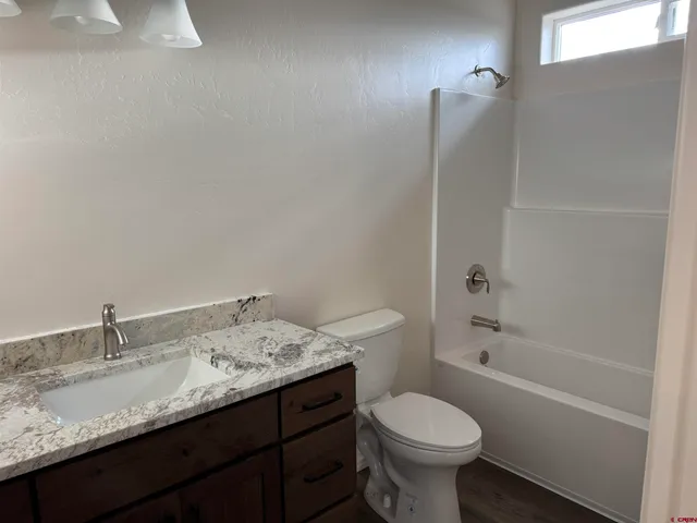 a bathroom with a granite countertop toilet sink and mirror