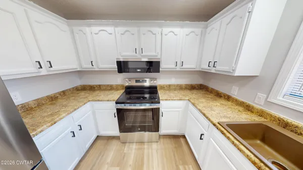 a kitchen with stainless steel appliances granite countertop a stove and white cabinets