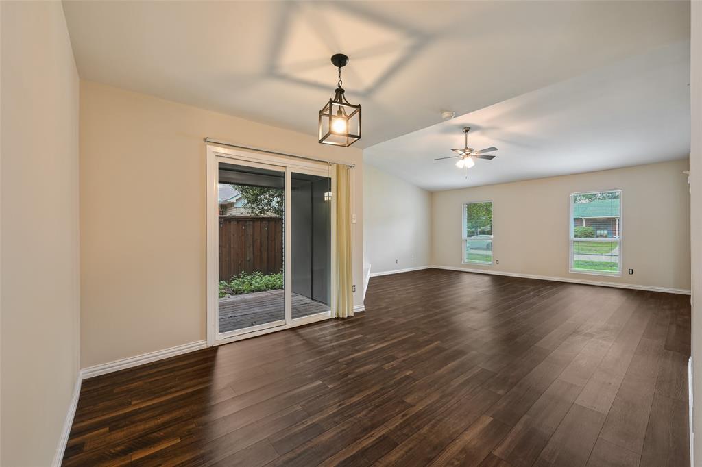 7318 Emory Oak Lane Dallas, TX 75249 - Photo 11 of 28 Spacious interior featuring dark wood-finish flooring, vaulted ceilings, and a sliding glass door leading to an outdoor area