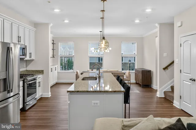 a kitchen with stainless steel appliances kitchen island a wooden floor and white cabinets