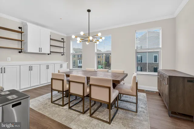 a view of a dining room and livingroom with furniture wooden floor a rug a chandelier