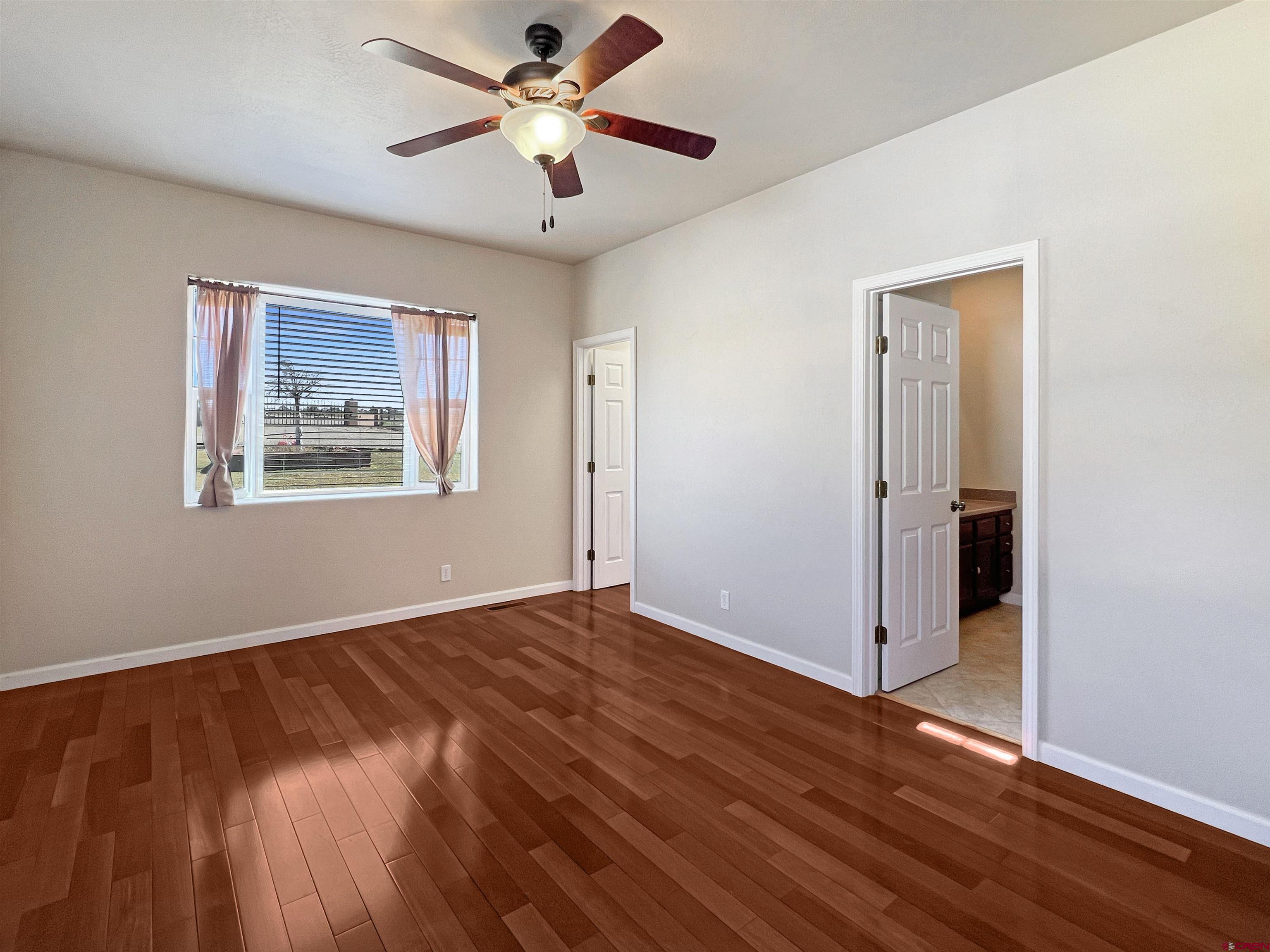 13723 Road 23 Cortez, CO 81321 - Photo 15 of 45 an empty room with wooden floor chandelier fan and windows
