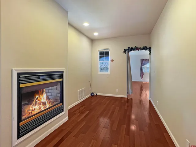 a view of an empty room with wooden floor a fireplace and a window