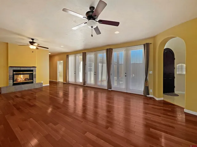 a view of an empty room with wooden floor and a ceiling fan
