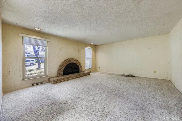 an empty room with a fireplace and windows