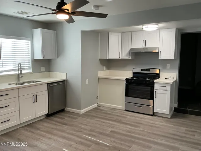 a kitchen with granite countertop a stove cabinets and wooden floor
