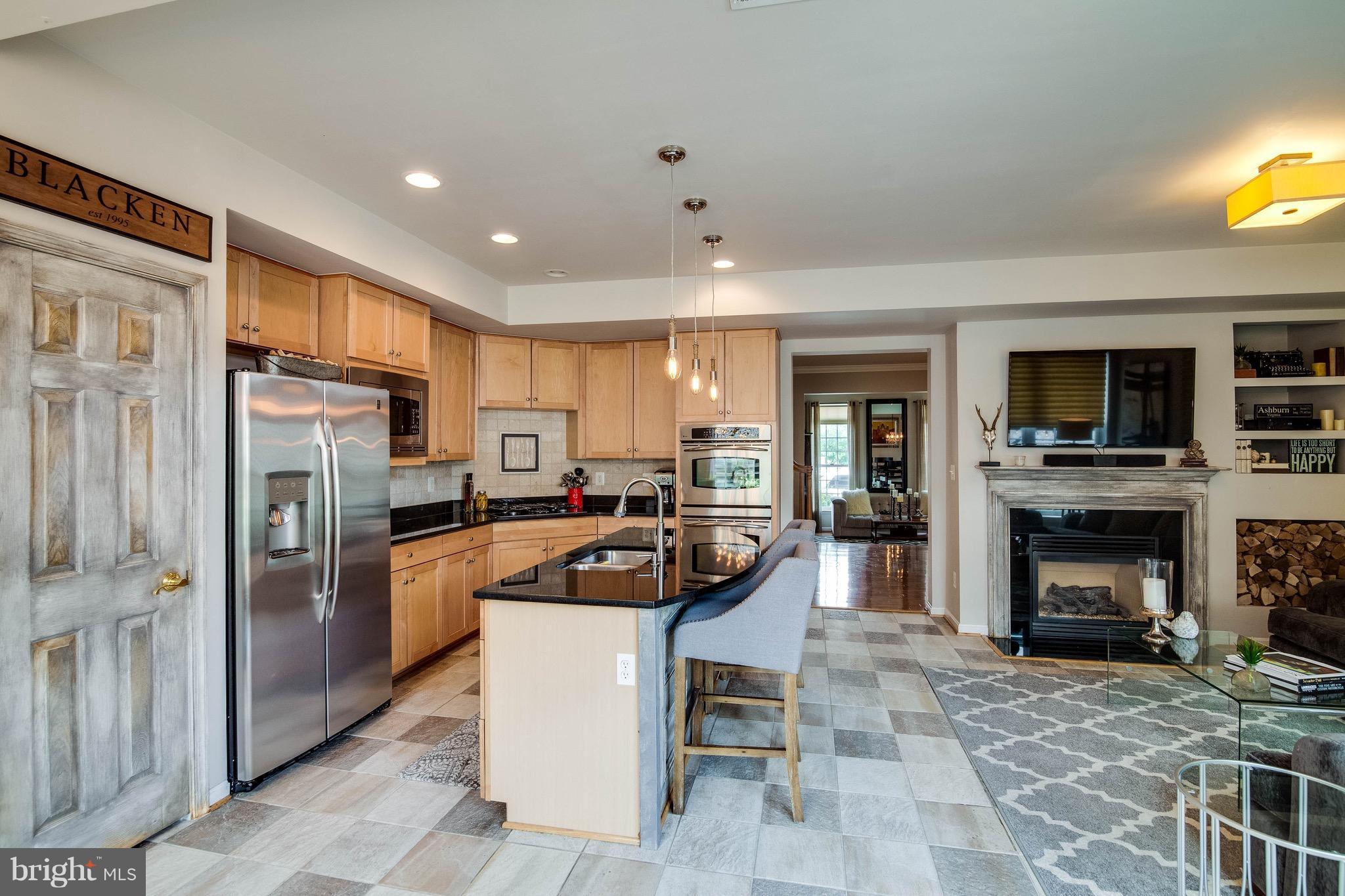 22960 Fanshaw Square Ashburn, VA 20148 - Photo 11 of 30 a kitchen with stainless steel appliances granite countertop a refrigerator a stove a microwave oven a dining table and chairs with wooden floor
