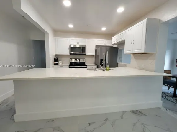 a kitchen with stainless steel appliances a sink a stove a microwave a refrigerator and cabinets