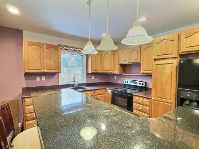 a kitchen with stainless steel appliances granite countertop a sink a stove and a refrigerator