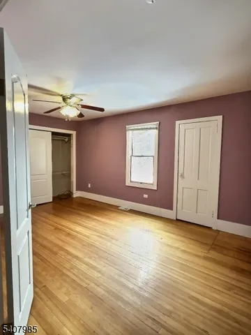 a view of empty room with wooden floor and fan
