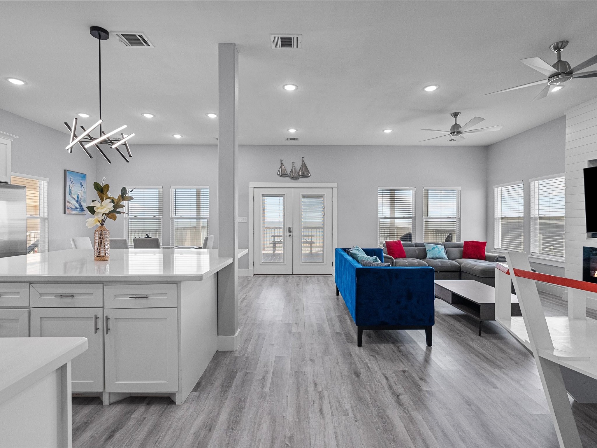 718 Beach Drive Surfside Beach, TX 77541 - Photo 11 of 49 Experience modern elegance in this kitchen with sleek white cabinetry, a spacious island with seating, and stainless steel appliances. The stylish blue tile backsplash and recessed lighting enhance the bright, open layout.