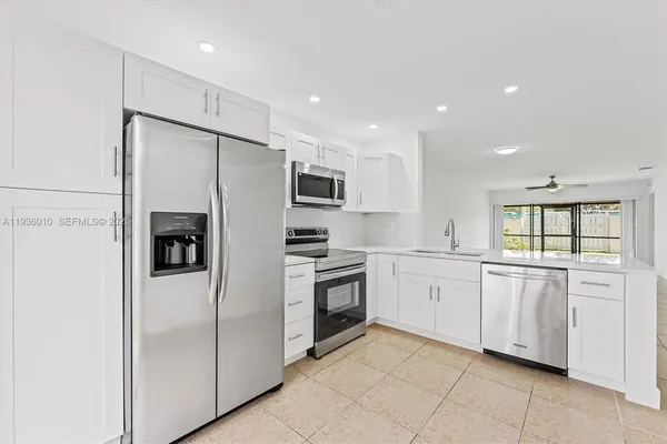 a kitchen with stainless steel appliances granite countertop white cabinets and refrigerator