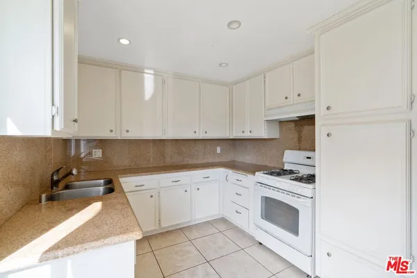 a kitchen with white cabinets and appliances
