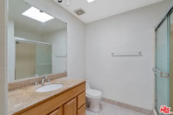 a bathroom with a granite countertop sink a toilet and a mirror