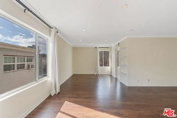 a view of a big room with wooden floor and windows