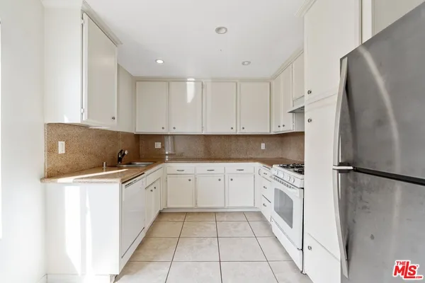 a kitchen with stainless steel appliances granite countertop a refrigerator sink and white cabinets