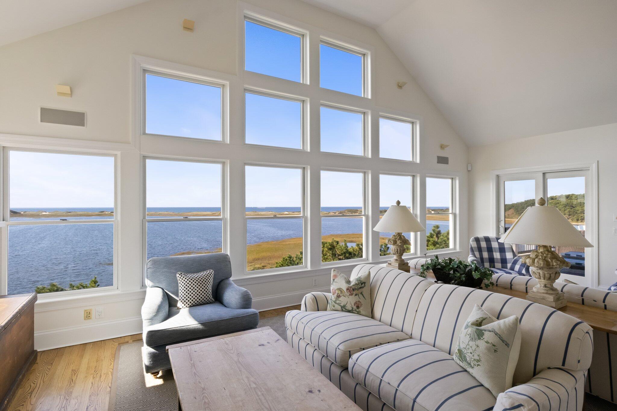 1035 Chequessett Neck Road Wellfleet, MA 02667 - Photo 22 of 86 a living room with furniture large windows wooden floor and a table