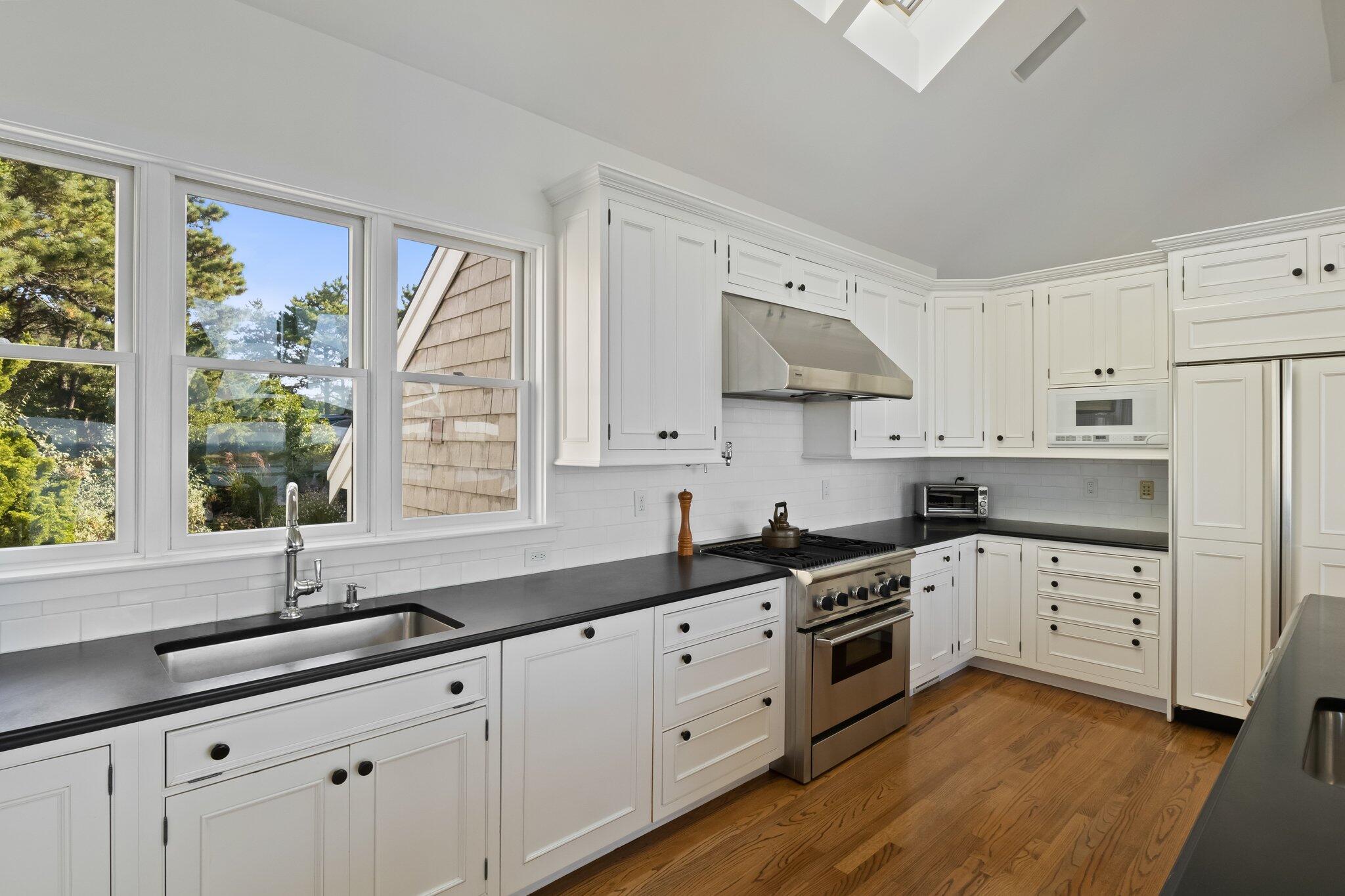 1035 Chequessett Neck Road Wellfleet, MA 02667 - Photo 10 of 86 a kitchen with granite countertop white cabinets white appliances a sink and a large window