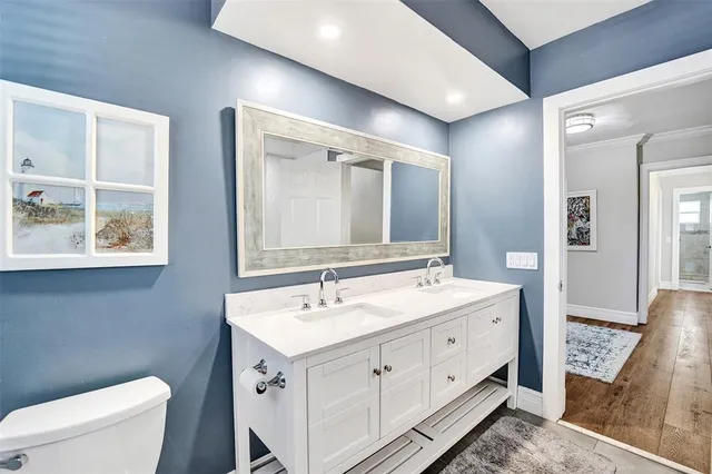 a spacious bathroom with a double vanity sink a mirror and a toilet