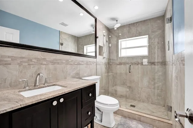 a bathroom with a granite countertop sink toilet and shower