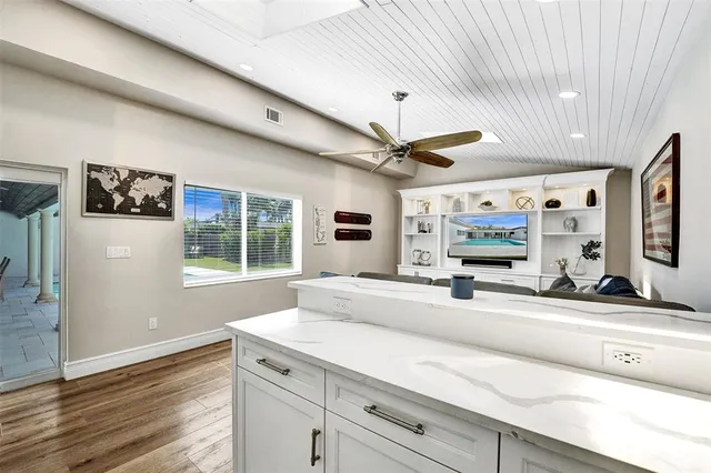 a living room with stainless steel appliances kitchen island granite countertop furniture and a flat screen tv