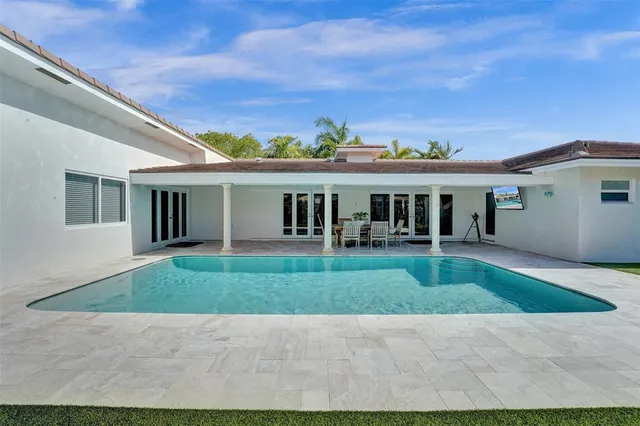 a view of house in front of a big yard with plants and large tree