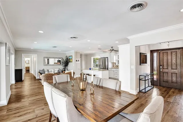 a view of a dining room and livingroom with furniture wooden floor a rug a fireplace and a chandelier