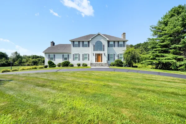 a front view of a house with garden and trees
