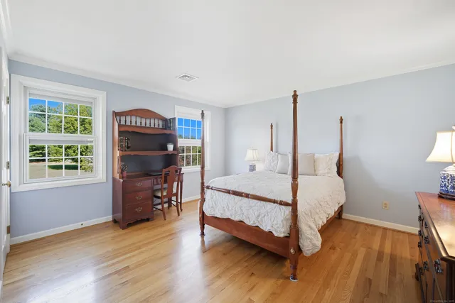 a bedroom with a bed wooden floor and window