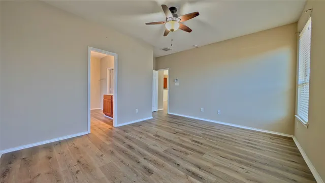 a view of empty room with wooden floor and fan