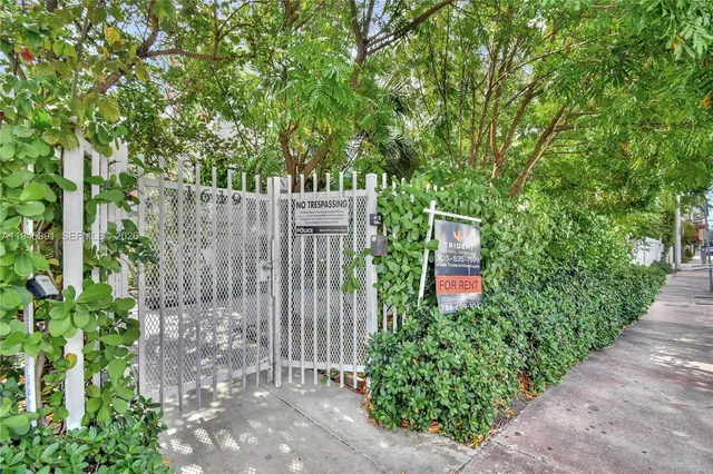a view of a pathway of a park with plants and a bench
