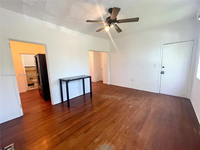 a view of a hallway with wooden floor and a ceiling fan