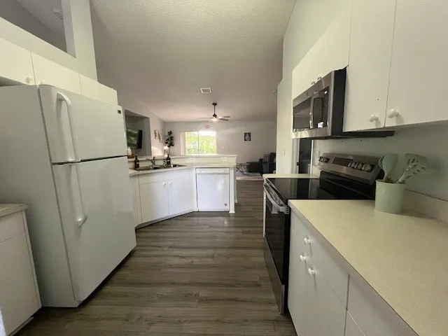 a kitchen with a refrigerator a stove top oven a counter space and wooden floor