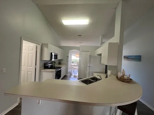 a large kitchen with a table chairs sink and refrigerator