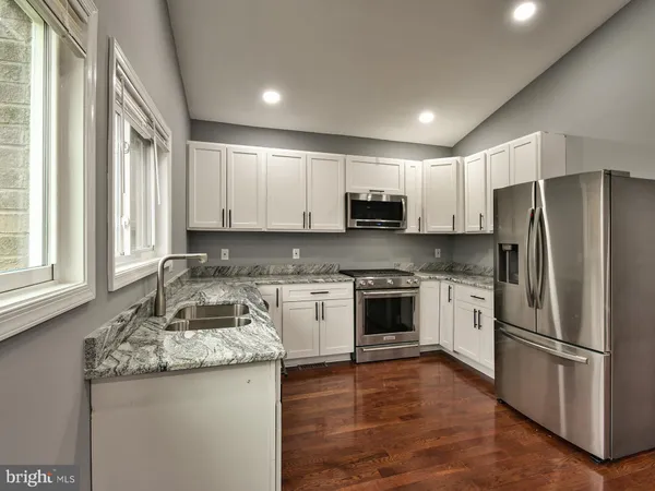 a kitchen with kitchen island granite countertop a stove a sink and a refrigerator