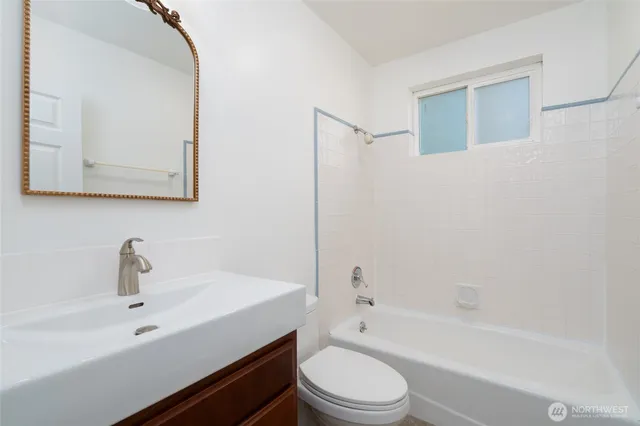 a bathroom with a bathtub shower sink vanity mirror and toilet